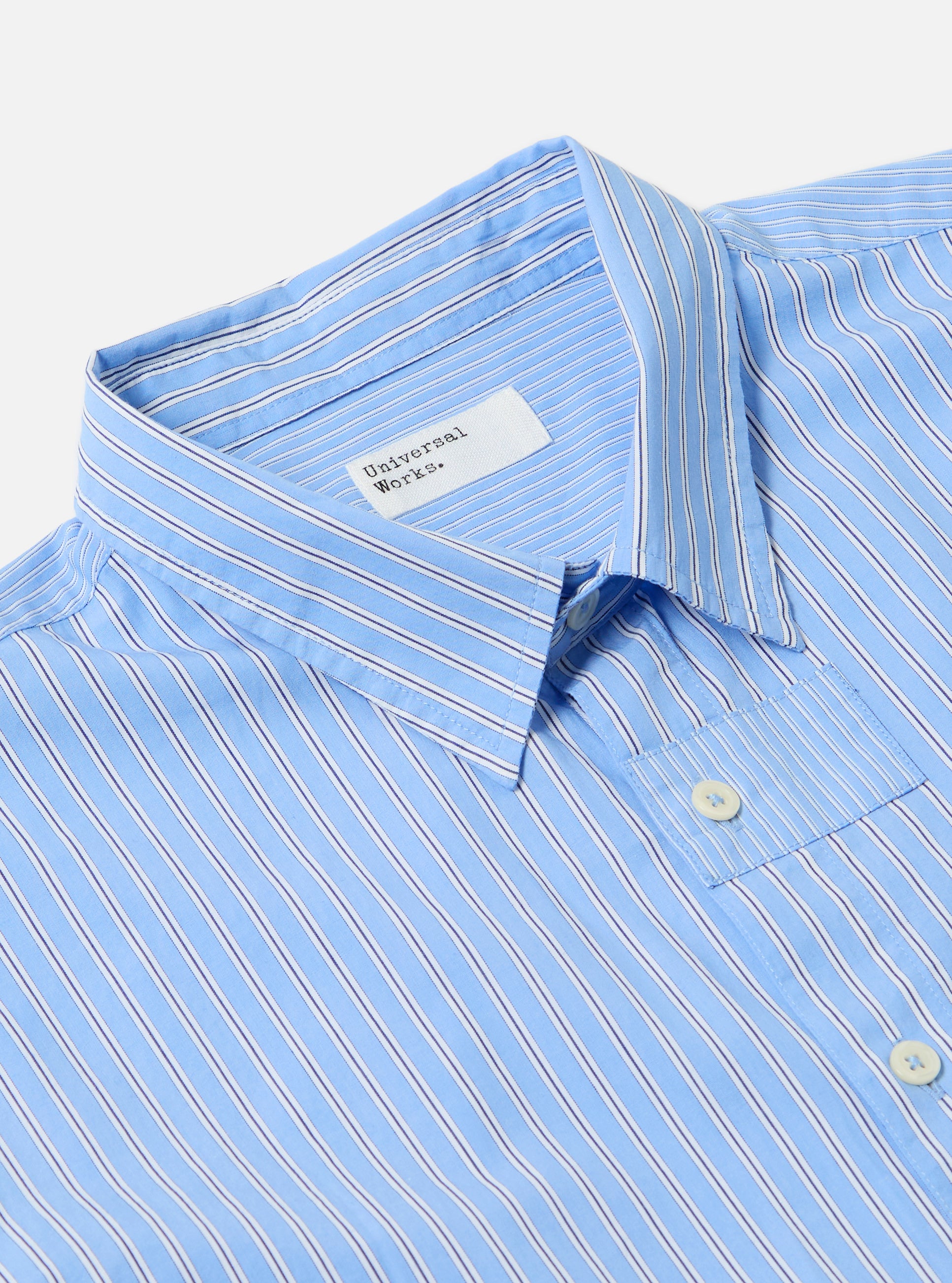 Close-up of the Blue Vila Stripes Patched Shirt on a white surface. The shirt is light blue with white and navy stripes and has a chest pocket.