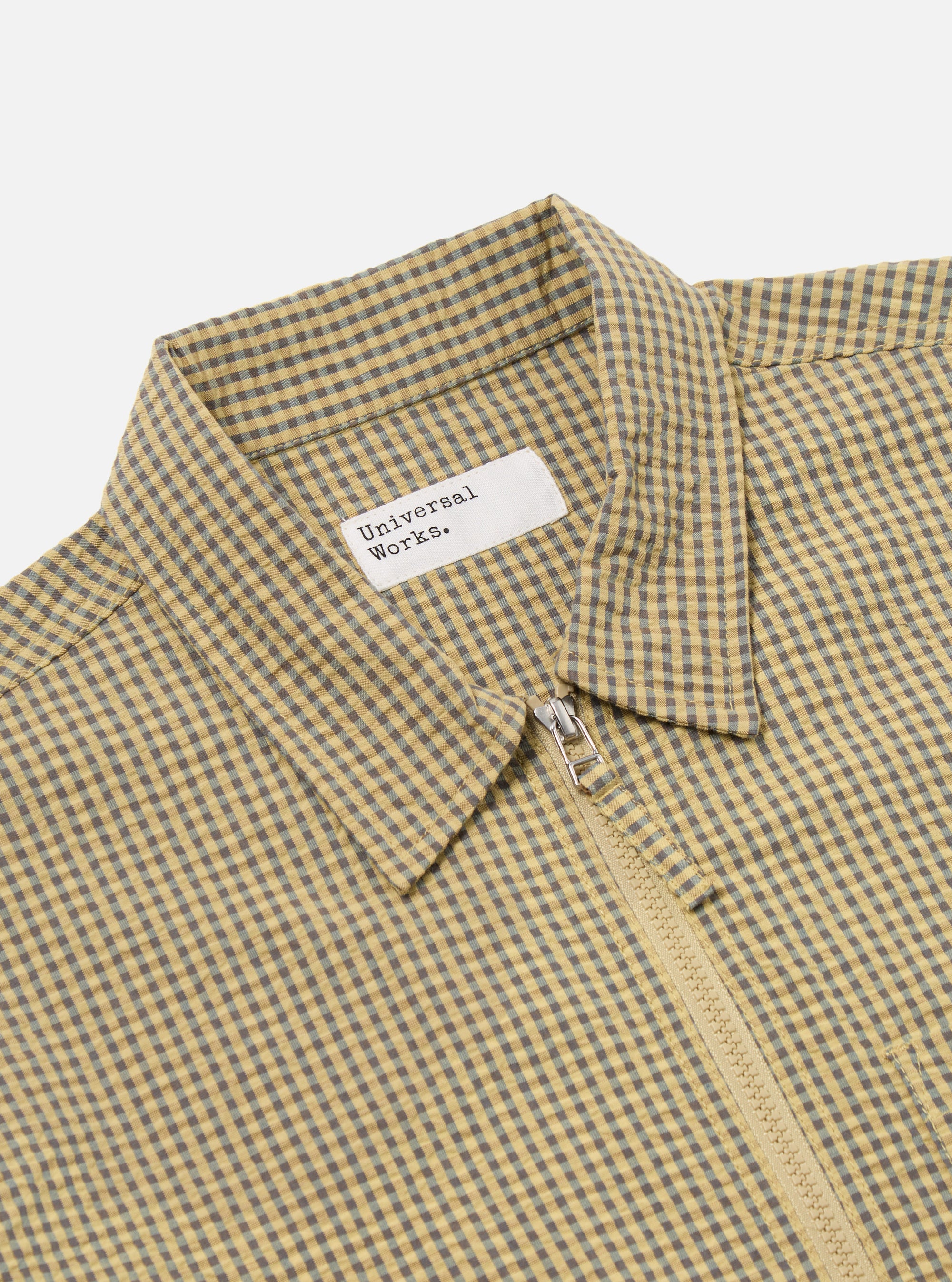 Close-up of the Yellow Japanese Seersucker Zip Uniform Jacket, showcasing its yellow and grey checkered pattern, seersucker texture, and zip closure. The jacket is displayed on a flat surface.