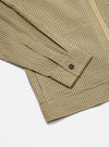 Close-up of the Yellow Japanese Seersucker Zip Uniform Jacket on a white surface. Shows the sleeve and hem, highlighting the yellow and gray checkered pattern and seersucker texture.
