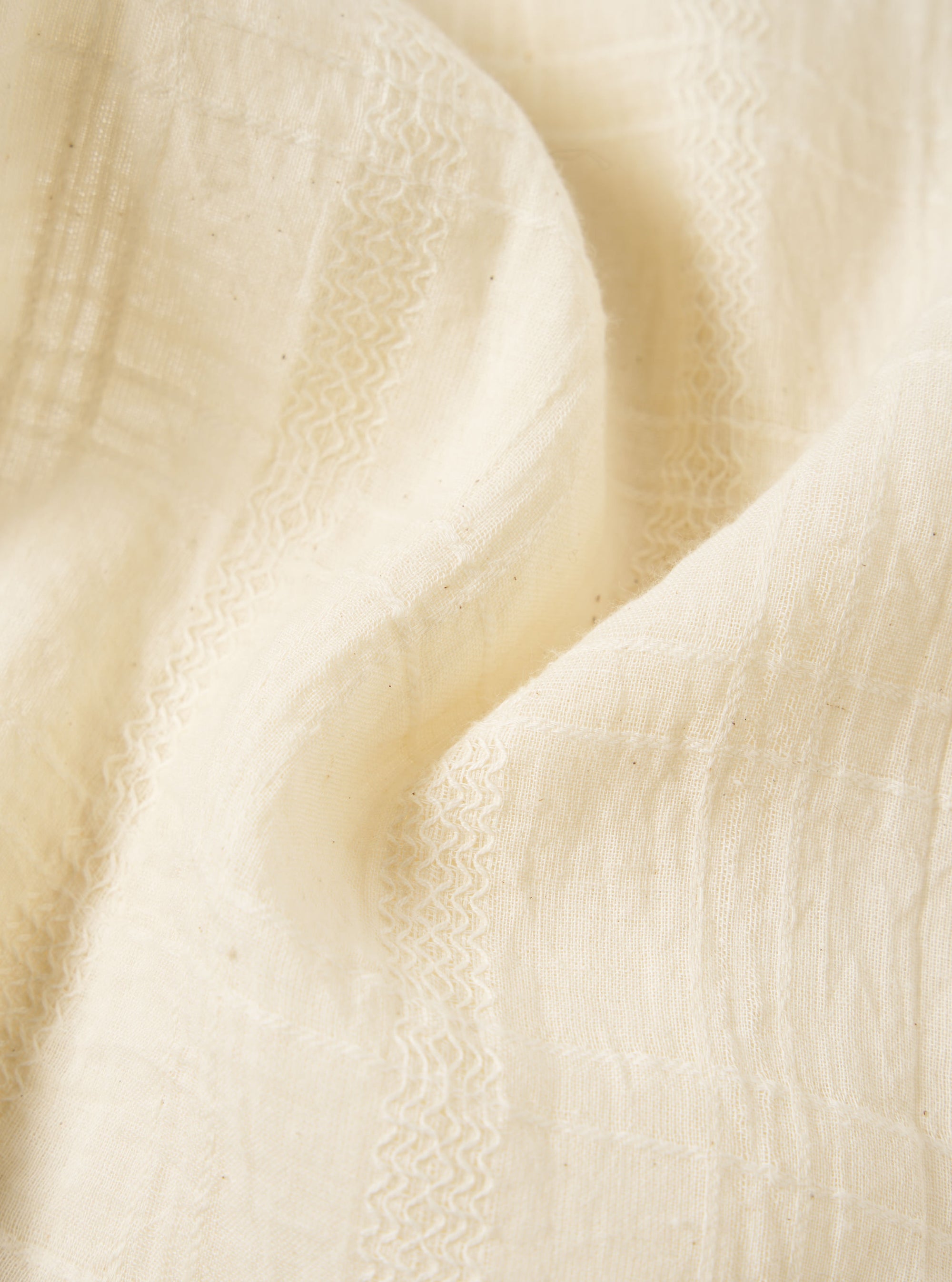 Close-up of the ecru Acapulco Weave Work Shirt, showing the textured weave and soft color. Fabric is draped on a flat surface.