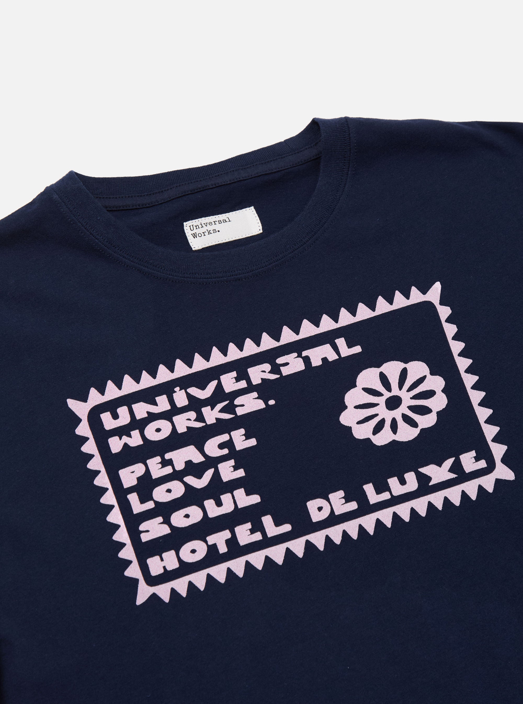 Close-up of the Navy/Pink Single Jersey Pickup Print Tee. The navy tee features a pink graphic print. Single jersey material. 