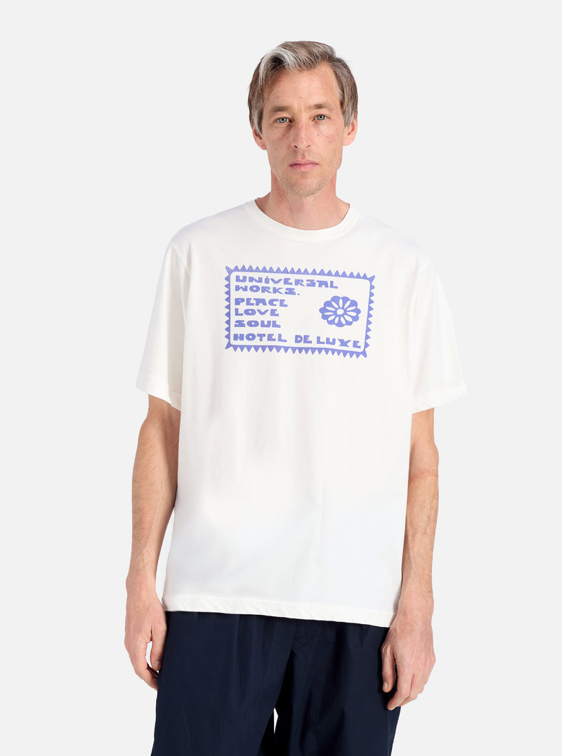 A model on a white background wears an Ecru/Yellow Single Jersey Pickup Print Tee. The tee has a blue graphic print. 