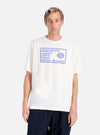 A model on a white background wears an Ecru/Yellow Single Jersey Pickup Print Tee. The tee has a blue graphic print. 