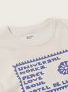 Close-up of the Ecru/Yellow Single Jersey Pickup Print Tee on a white surface. The tee is ecru with a yellow print. The image focuses on the collar and upper chest.