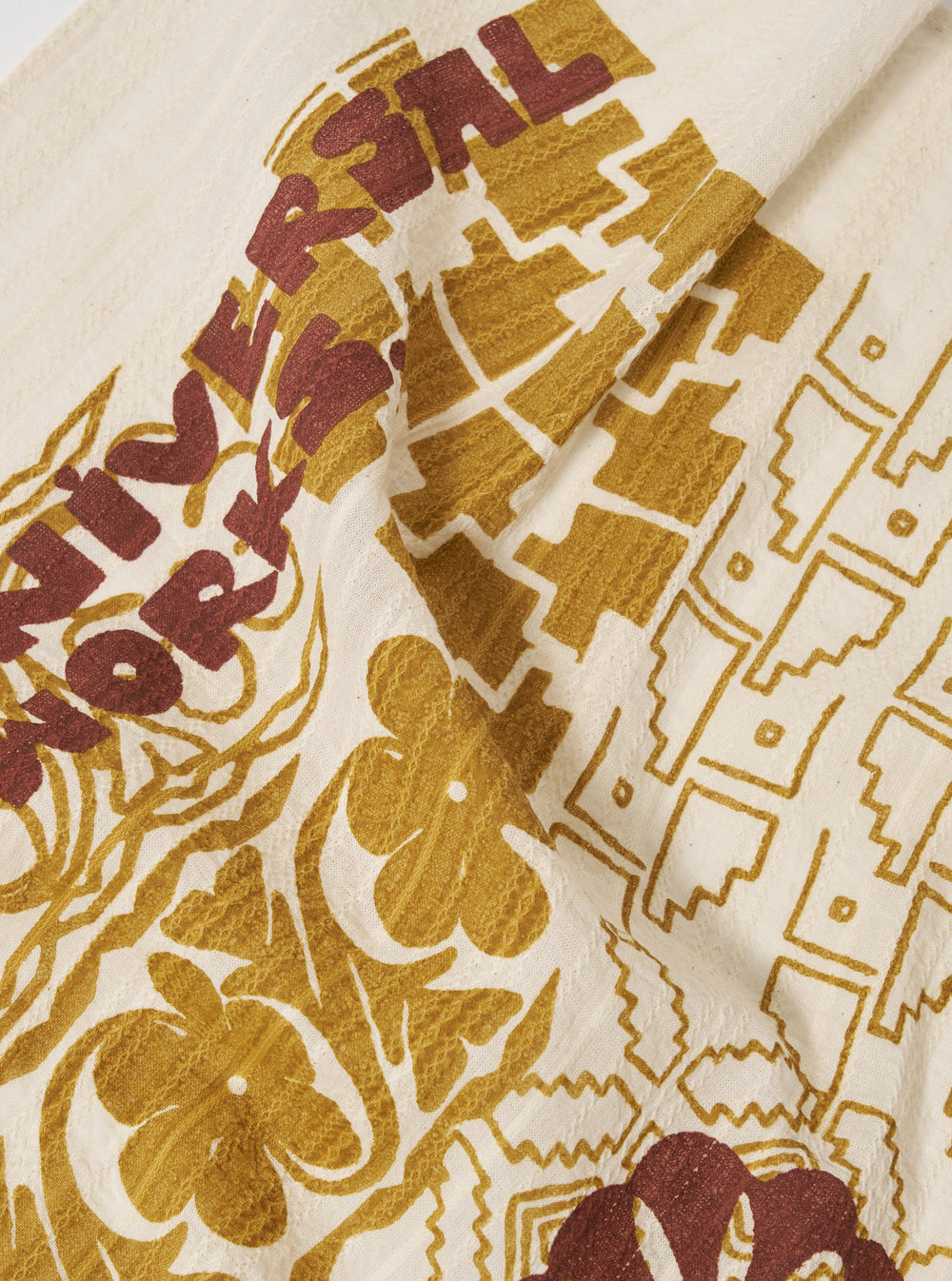 Close-up of the Ecru Acapulco Weave Kingsman Neckerchief, featuring a detailed floral and geometric pattern in ecru, gold, and brown hues on a textured fabric.