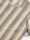 Close-up of the Grey/Yellow Cotton Lattice Road Shirt. The shirt features a striped pattern with grey, yellow, and cream colors. The fabric has a lattice texture. The shirt is laid flat on a white surface.