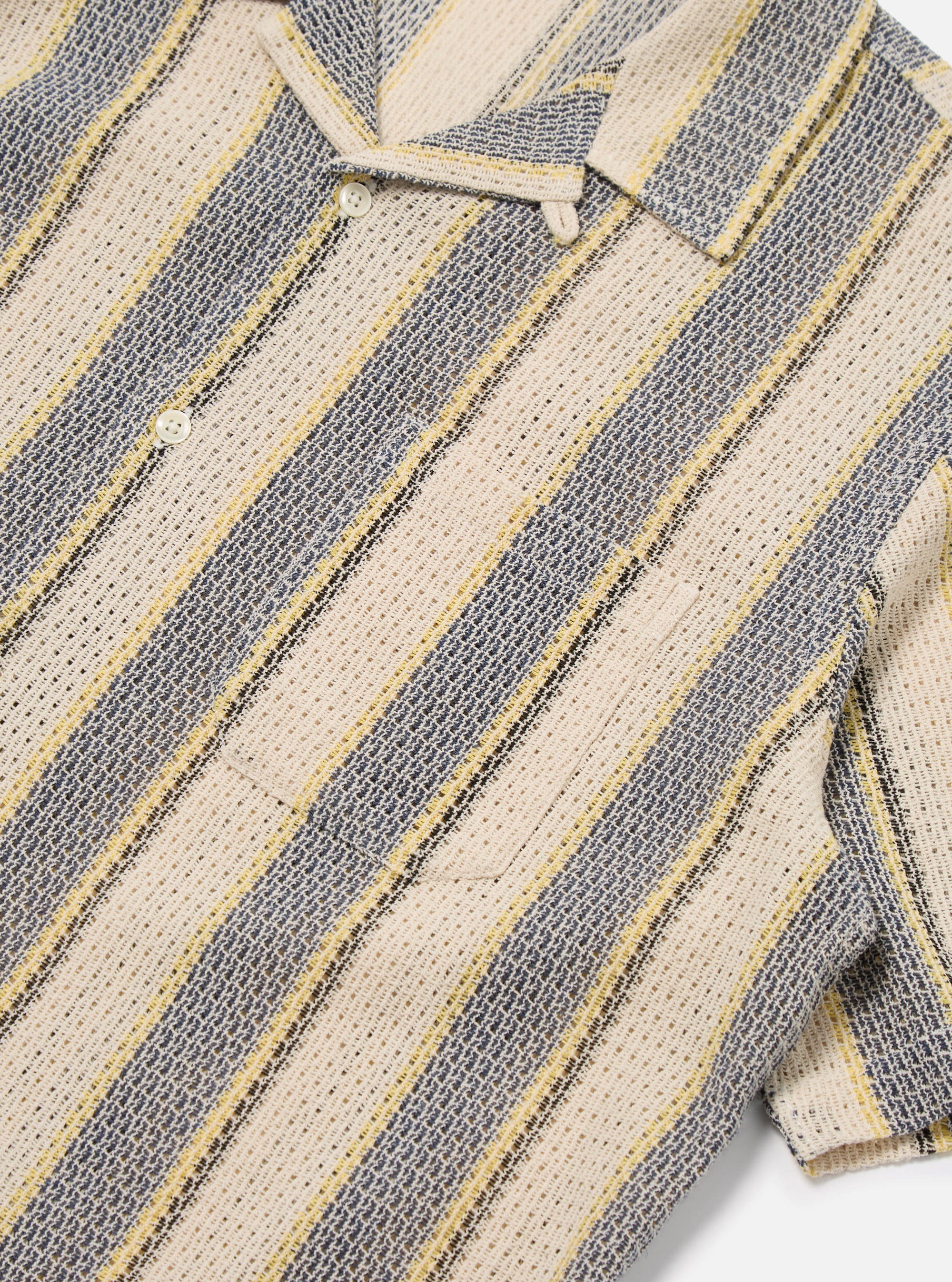 Close-up of the Grey/Yellow Cotton Lattice Road Shirt. The shirt features a striped pattern with grey, yellow, and cream colors. The fabric has a lattice texture. The shirt is laid flat on a white surface.