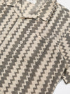 Close-up of the Charcoal Cotton Lattice Road Shirt on a white surface. The shirt has a black and cream lattice pattern and short sleeves.