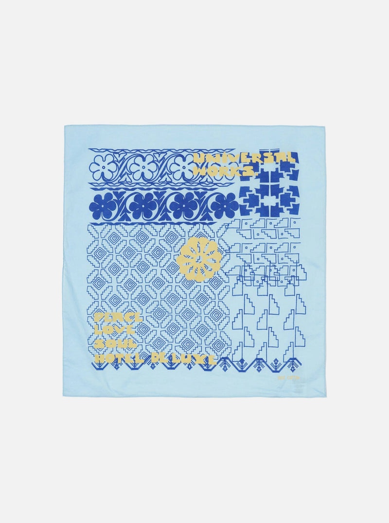 Flat lay of a Blue Cambric Kingsman Neckerchief on a white surface. The neckerchief has blue and yellow patterns.