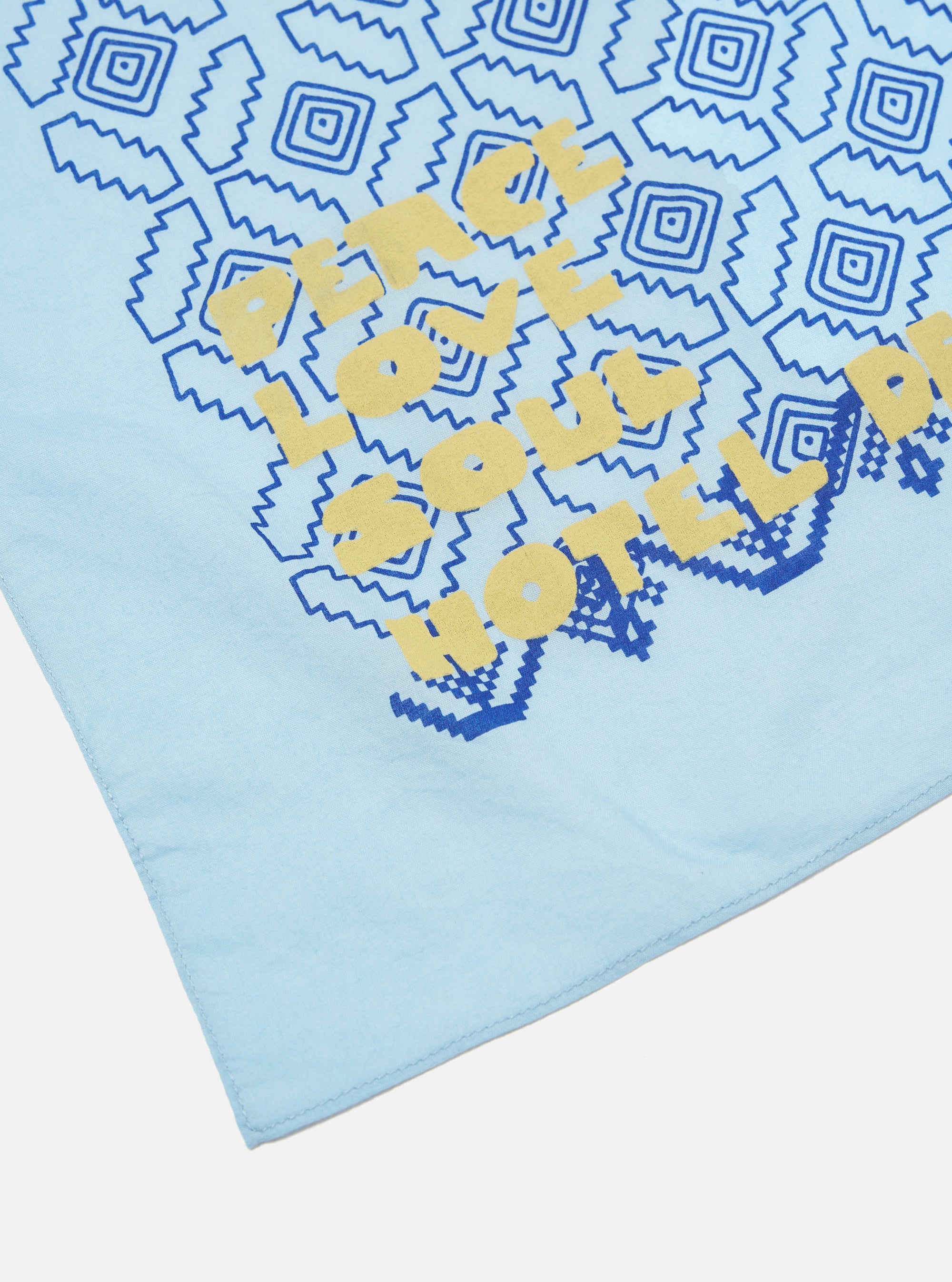 Close-up of the Blue Cambric Kingsman Neckerchief on a white surface. The neckerchief has a blue pattern and yellow lettering.