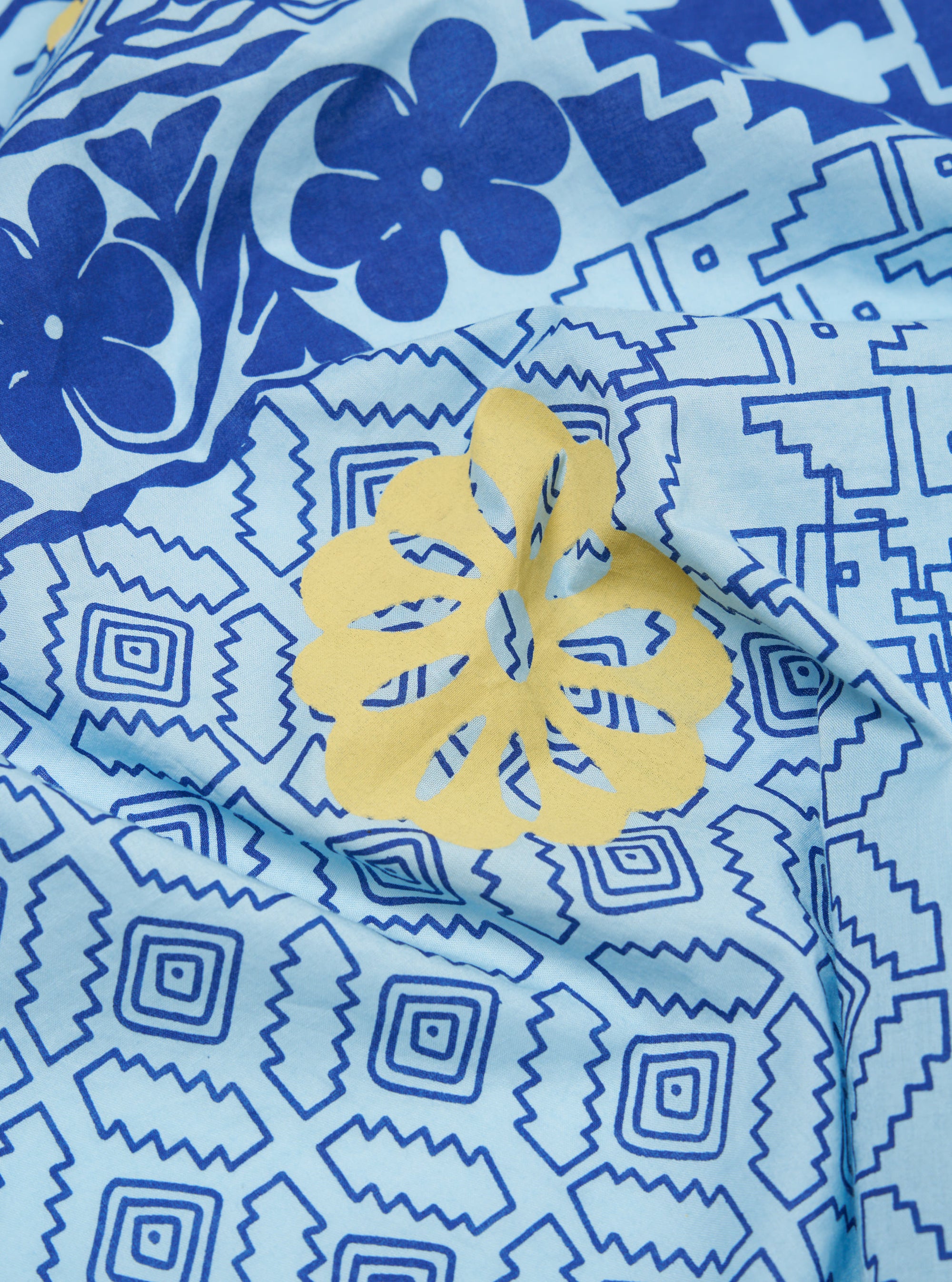 Close-up of the Blue Cambric Kingsman Neckerchief. The light blue fabric features a dark blue floral and geometric pattern, with a yellow floral accent.