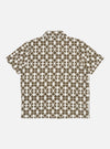 The Ecru/Mud Mitla Print Jersey Newlyn Polo shirt on a white background. The polo is ecru with a mud-colored geometric print. The shirt is short-sleeved.