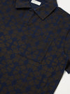 Close-up of the Navy/Brown Mitla Print Jersey Newlyn Polo, showcasing the unique pattern and jersey material. The polo is displayed on a flat surface.
