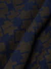 Close-up of the Navy/Brown Mitla Print Jersey Newlyn Polo fabric. The jersey material features a geometric print in navy and brown hues.