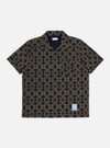 The Navy/Mud Mitla Print Jersey Newlyn Polo shirt on a white background. The polo is patterned with a navy and mud geometric print.
