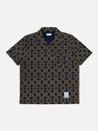 The Navy/Mud Mitla Print Jersey Newlyn Polo shirt on a white background. The polo is patterned with a navy and mud geometric print.