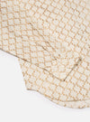 Close-up of the Camel Mitla Weave Work Shirt on a white surface. The shirt is light with a brown woven pattern. The sleeve and buttons are visible.