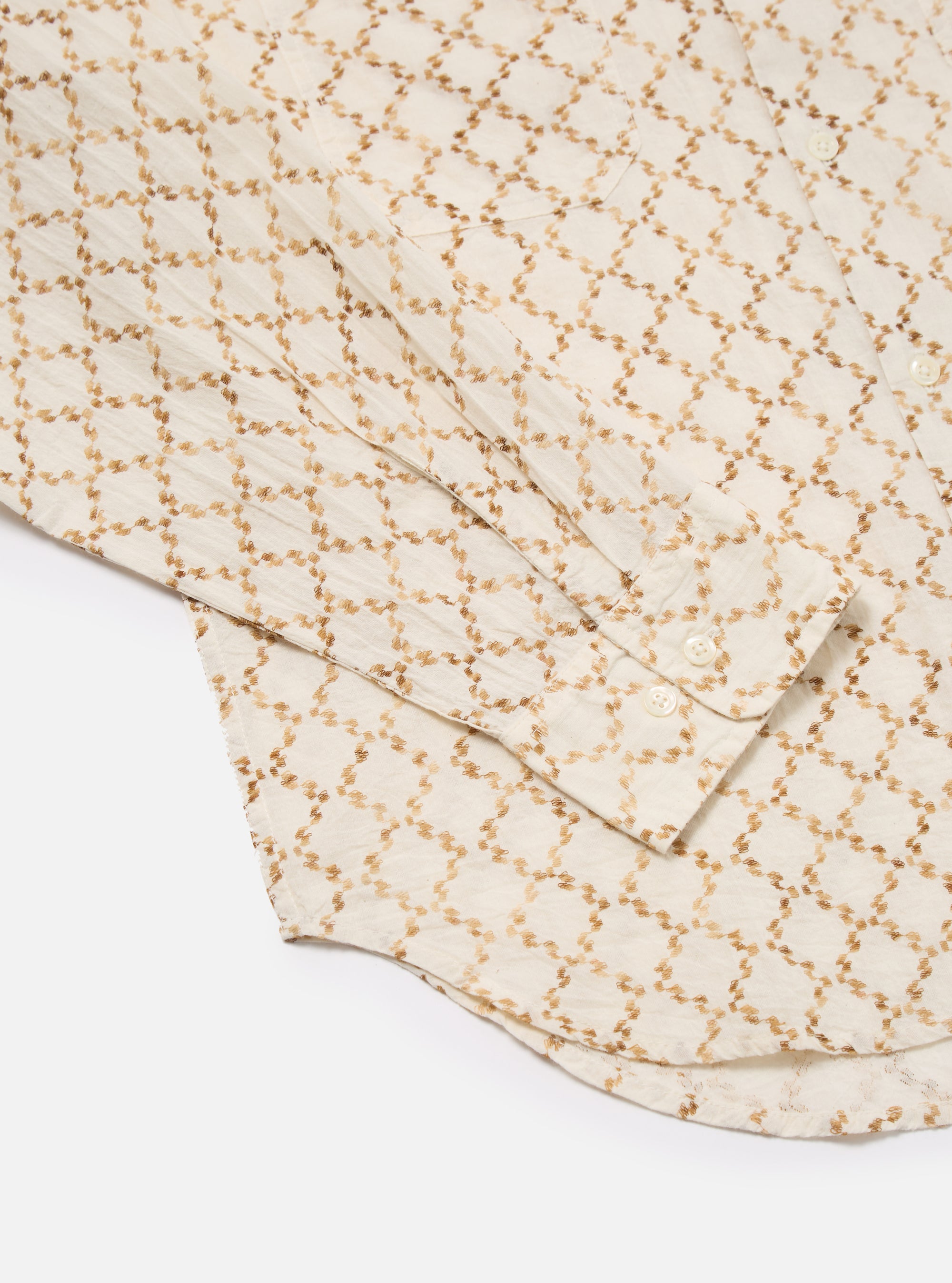 Close-up of the Camel Mitla Weave Work Shirt on a white surface. The shirt is light with a brown woven pattern. The sleeve and buttons are visible.