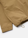 Close-up of the Dark Sand Peach Recycled Nylon Liam Jacket. Shows the sleeve and hem detail with drawstring. The jacket is on a white surface.