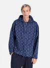 A man poses in a Navy Mitla Print Cord Liam Jacket. The blue jacket has a geometric pattern. He stands against a white background with his hand in his pocket.