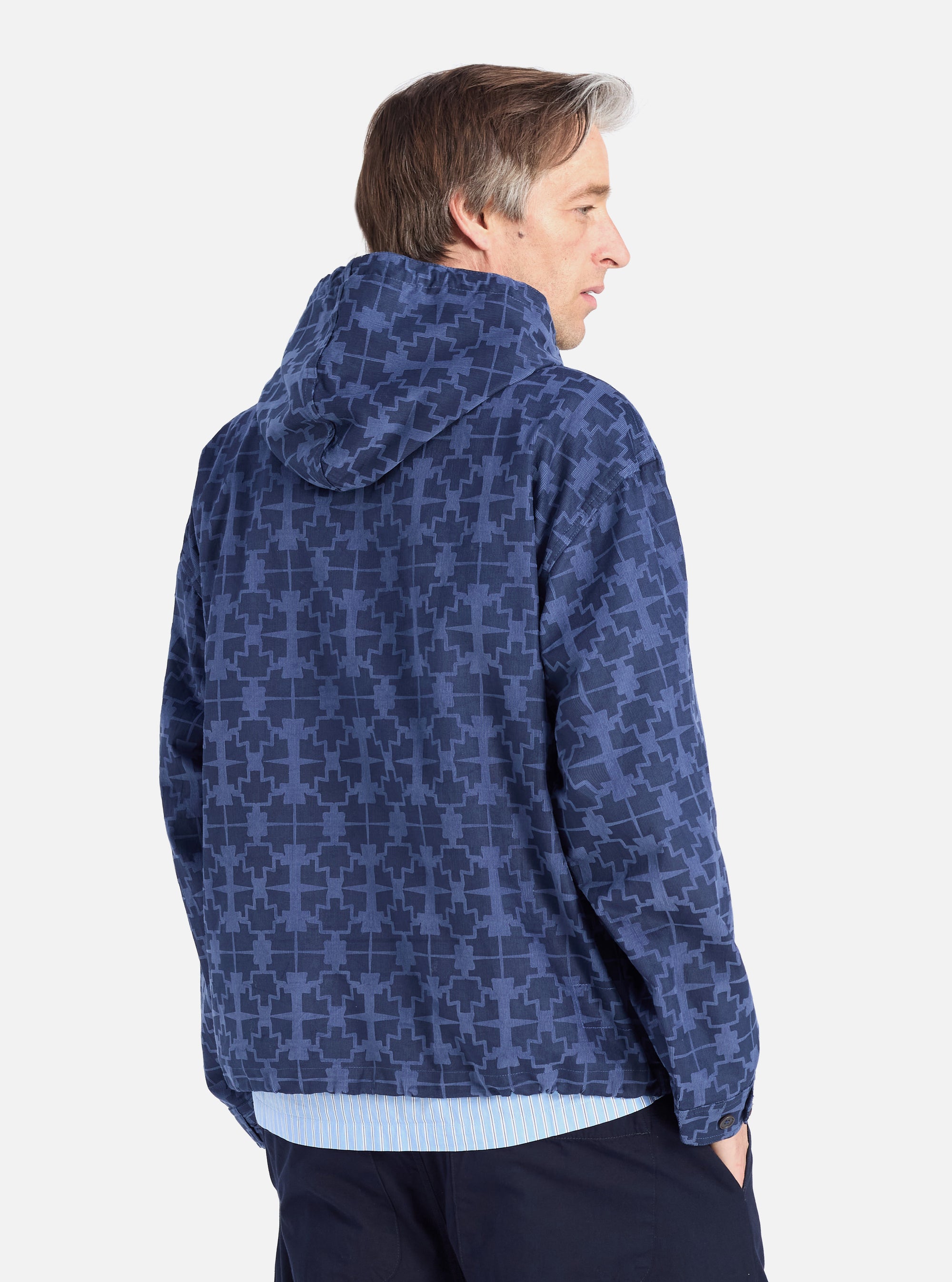 Profile shot of a model wearing the Navy Mitla Print Cord Liam Jacket. The jacket is blue with a geometric print, corduroy material, and a relaxed fit. White background.