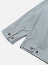 Close-up of the Indigo Reworked Jean Cloth Rose Bowl Jacket sleeve on a white surface. Light blue denim with brown buttons.