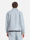 Back view of a model wearing the Indigo Reworked Jean Cloth Rose Bowl Jacket and matching pants. Light blue denim material with brown buttons. Shot against a white background.