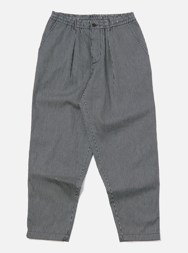 Studio shot of Indigo Hickory Stripe Denim Pleated Track Pant on a white background. The pants are striped with a relaxed fit.