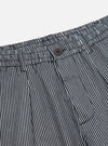 Close-up of the Indigo Hickory Stripe Denim Pleated Track Pant. Features include a button closure, pleated design, and denim material. Shot on a plain white background.