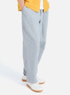 A model wears the Indigo Reworked Jean Cloth Oxford Pant, a light blue, loose-fitting trouser. Shot in a studio setting with a white background.