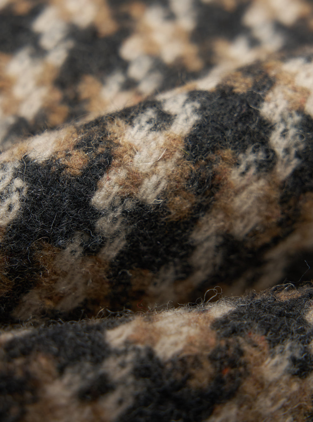 Close-up of the tweed fabric of the Sand Cortina Tweed Long Swing Coat, showing the texture and pattern in shades of sand, brown, and black.