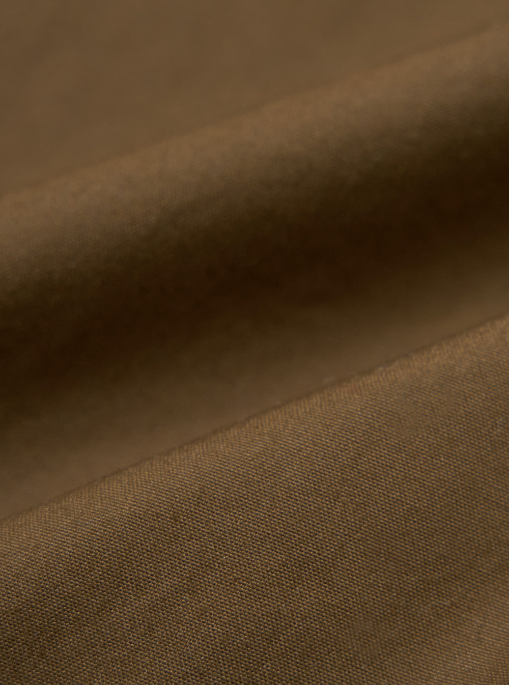 Close-up of the brown British wax cotton Boston Parka fabric. The durable material has a subtle texture. Ideal for a stylish, weather-resistant coat.