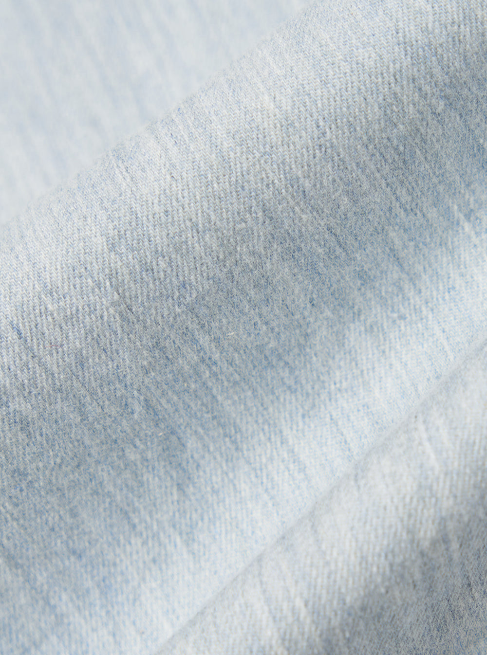 Close-up of the Sky Blue Brushed Organic Cotton Square Pocket Shirt fabric. Soft, brushed texture in a light sky blue hue. The shirt is neatly folded on a white surface.