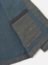 The Grey/Blue Jacquard Weave Field Jacket is shown from the back, laid flat against a solid white background. The image highlights the straight-cut hem, plain cuffs, and the intricate grey and blue textured jacquard pattern throughout the garment.