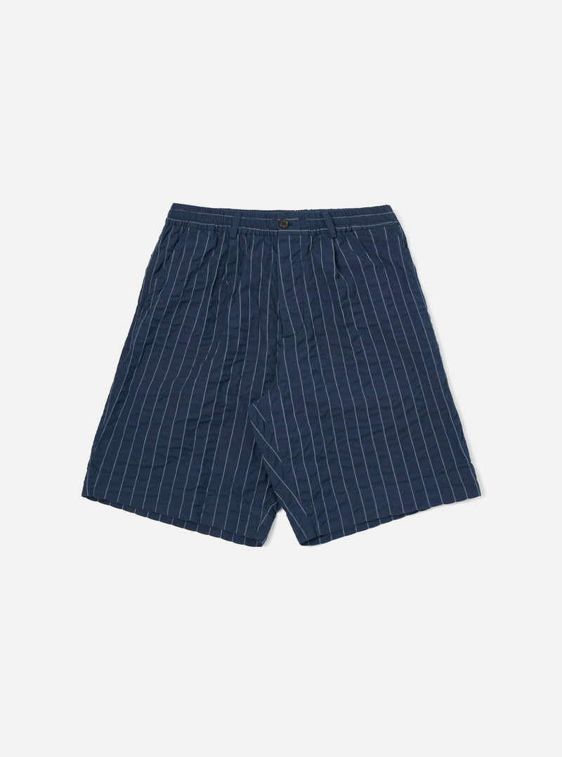 A pair of Navy Chester Stripe Pleated Track Shorts is shown laid flat against a solid white background. The shorts feature a vertical white pinstripe pattern on a navy base, an elasticated waistband with a button closure, a single pleat on each leg, and two side pockets.