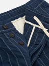 The Navy Chester Stripe Pleated Track Short is displayed from a rear perspective, laid flat against a solid white background. The image highlights the elasticated waistband and two rear pockets, including one buttoned jetted pocket and one button-close flap pocket. The navy blue fabric features a subtle vertical stripe pattern.