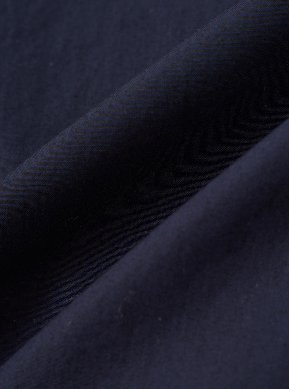 A close-up fabric swatch of the Navy Paper Touch Cotton Vacation Short displays the smooth and crisp texture of the navy blue paper-touch cotton fabric. The image focuses on the fine weave and consistent color of the material.