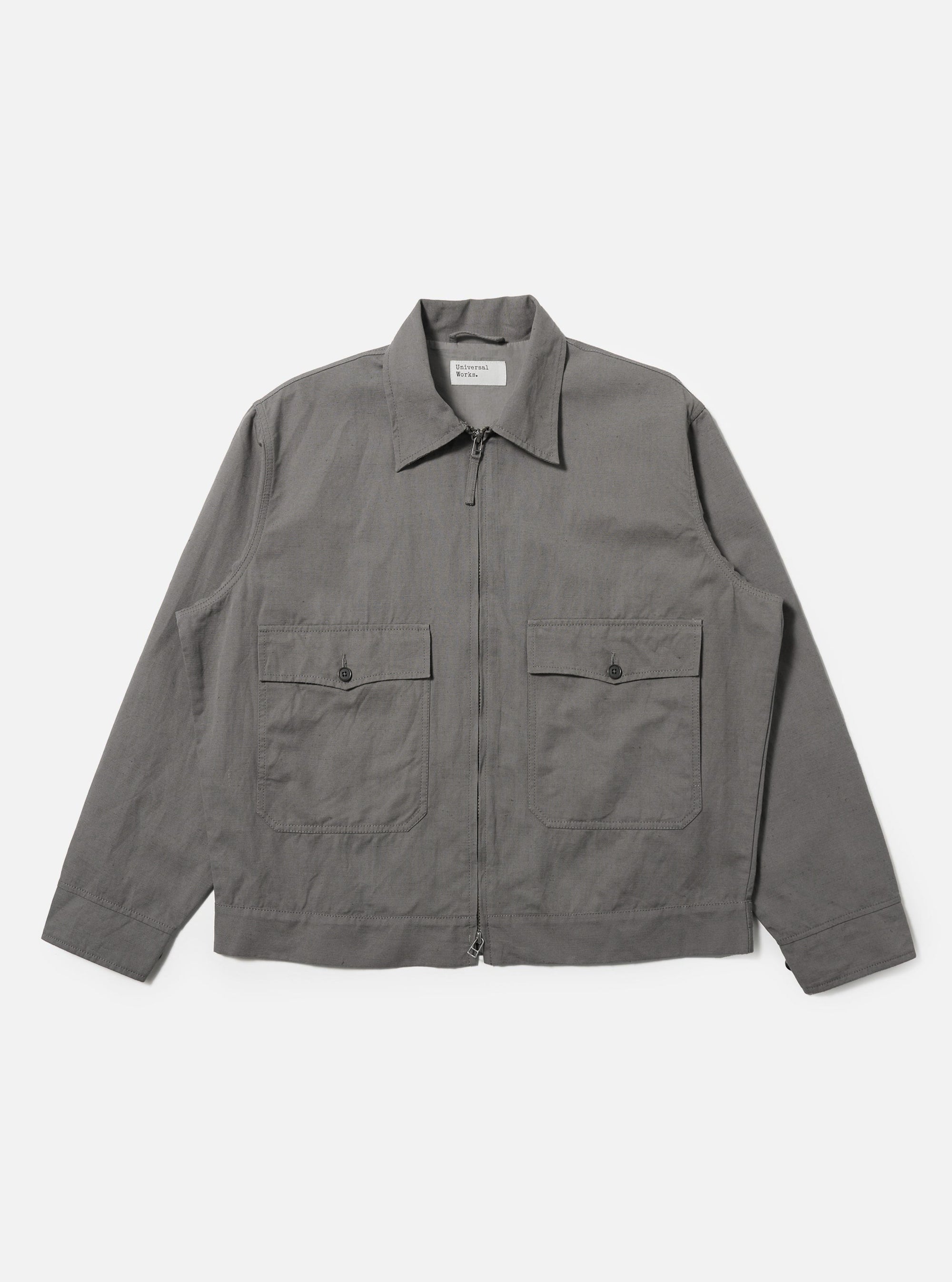 A Mid Grey Linen Slub Weave E130 Jacket is shown laid flat against a solid white background. The jacket features a classic pointed collar, a full button-down front, and two large rectangular patch pockets at the hips. The mid-grey linen fabric exhibits a distinct textured slub weave.