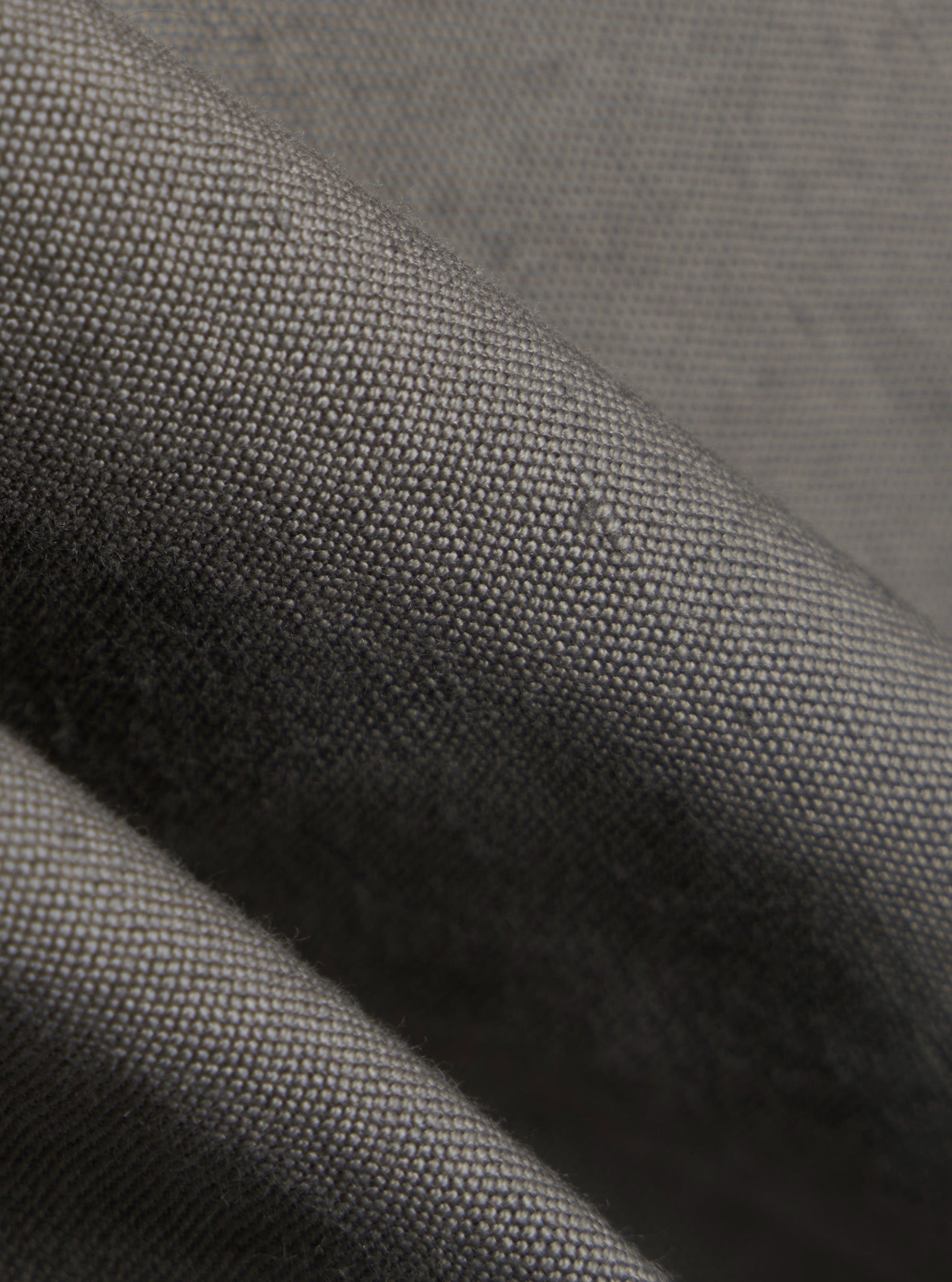 A close-up fabric swatch of the Mid Grey Linen Slub Weave E130 Jacket highlights the textured, slubbed appearance of the linen and cotton blend. The image focuses on the weave and the mid-grey color of the material.