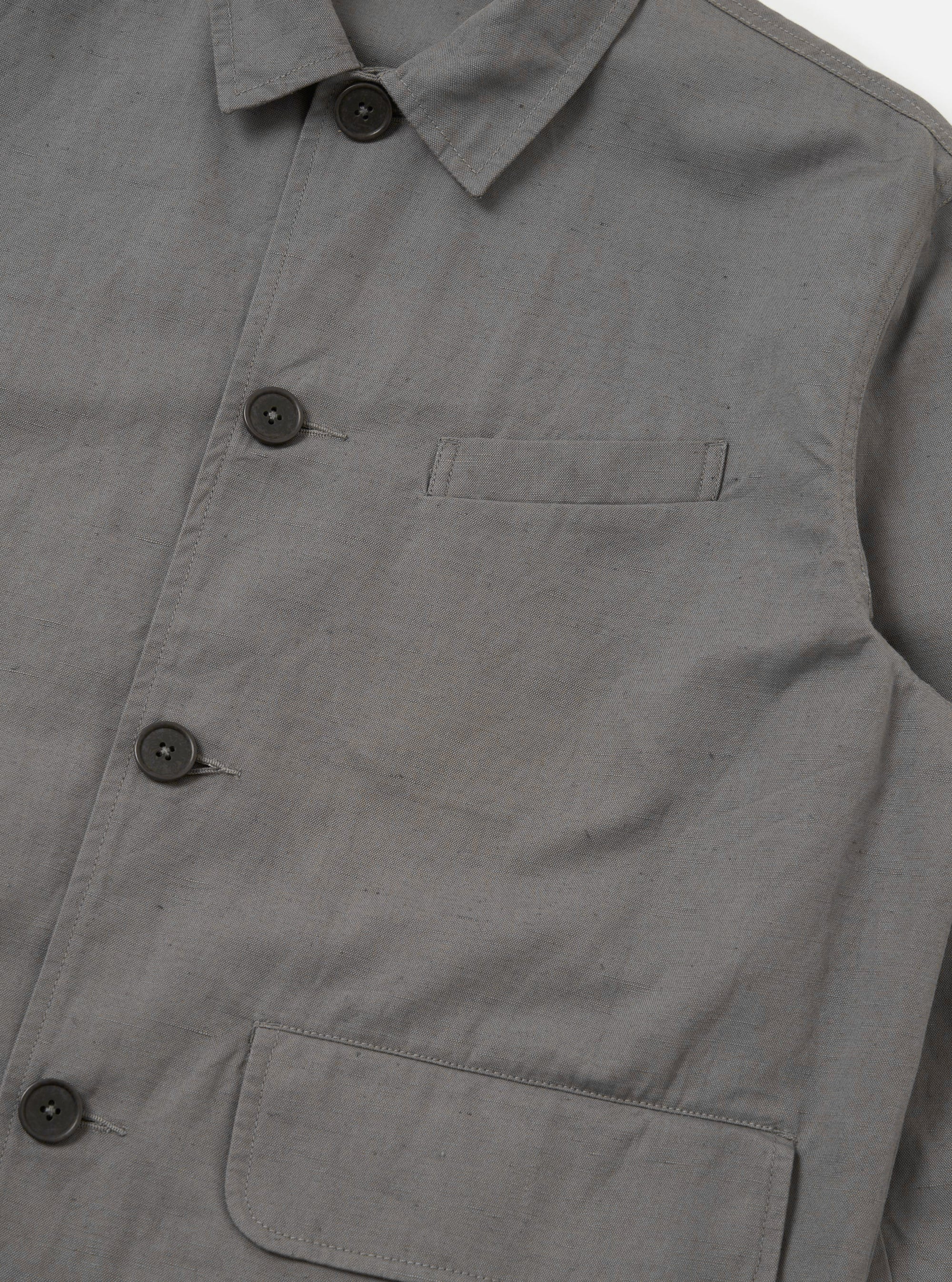 The Mid Grey Linen Slub Weave Franck Jacket is shown from the back as a flat lay against a plain white background. The image highlights the jacket's structured shoulders, a central vertical seam, and the textured appearance of the mid-grey linen-cotton blend fabric.