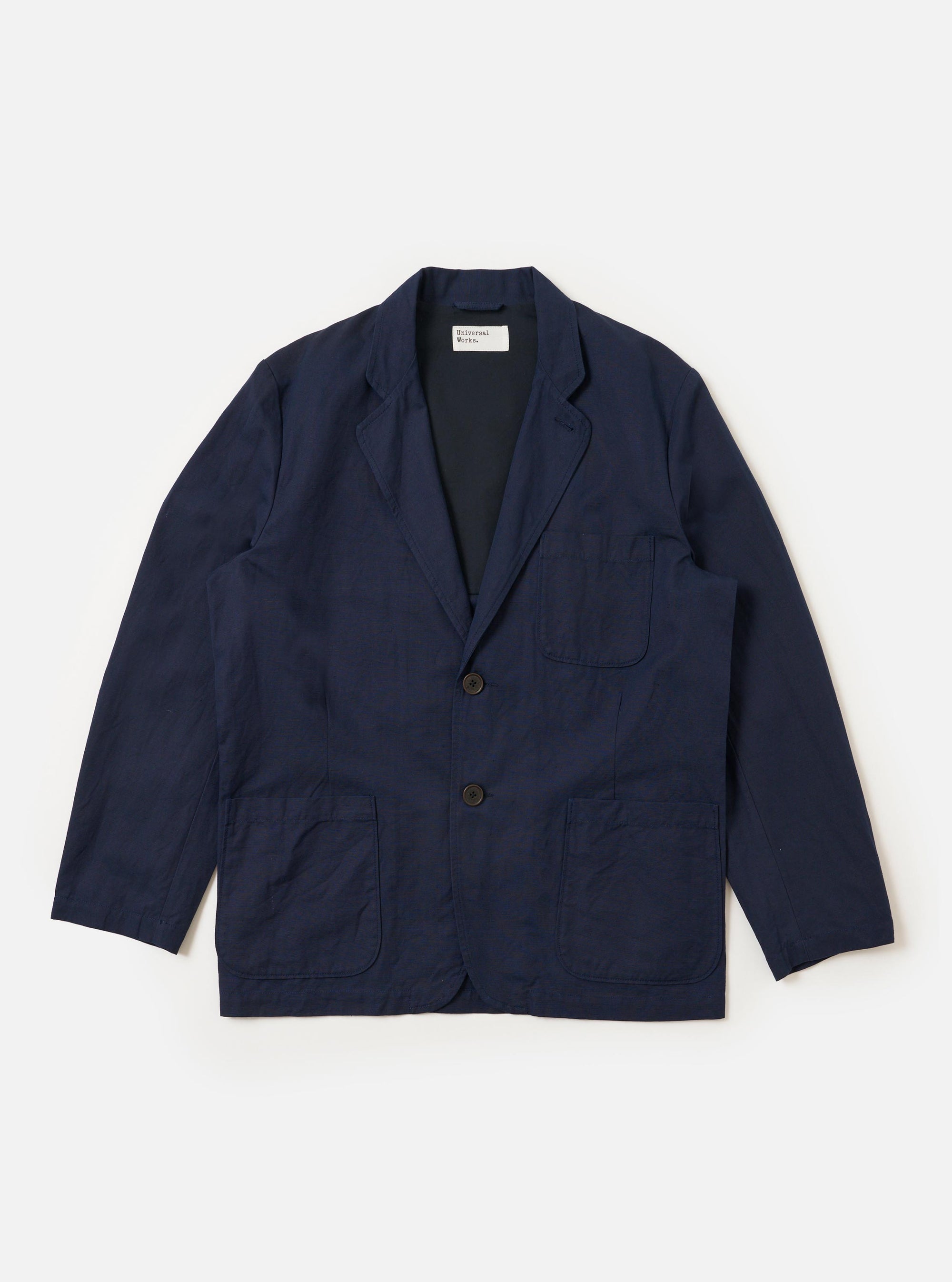 The Navy Linen Slub Weave Two Button Jacket is displayed as a flat lay against a plain white background. The jacket features notched lapels, a two-button front closure, and two flap pockets at the waist. The navy blue fabric has a prominent slub texture with visible variations in the weave.