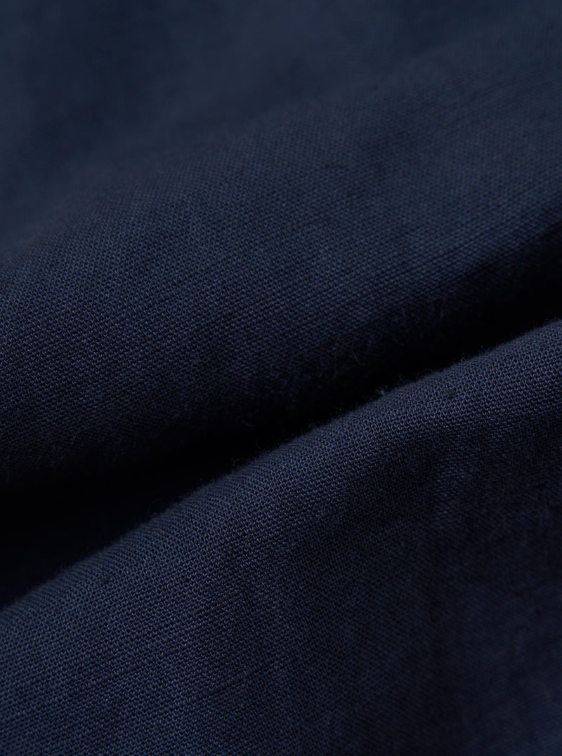A close-up, square fabric swatch of the Navy Linen Cotton Shirting Dizzy Jacket is shown against a neutral, out-of-focus background. The image highlights the fine, textured weave of the navy blue linen-cotton blend material.