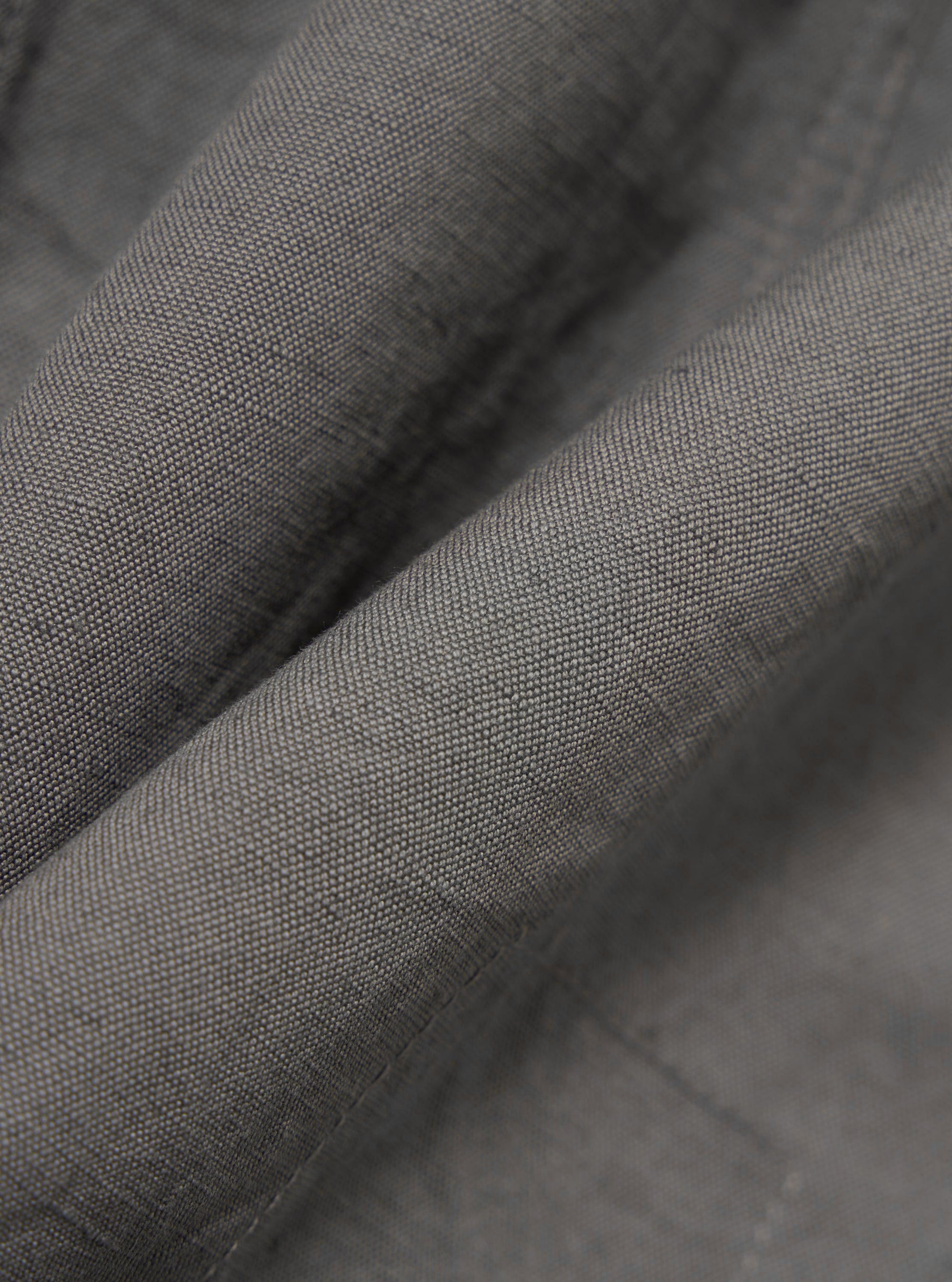 A close-up, square fabric swatch of the Mid Grey Linen Slub Weave Bakers Jacket highlights the textured, irregular slubbed surface of the linen and cotton blend. The mid-grey fabric features a visible woven pattern.