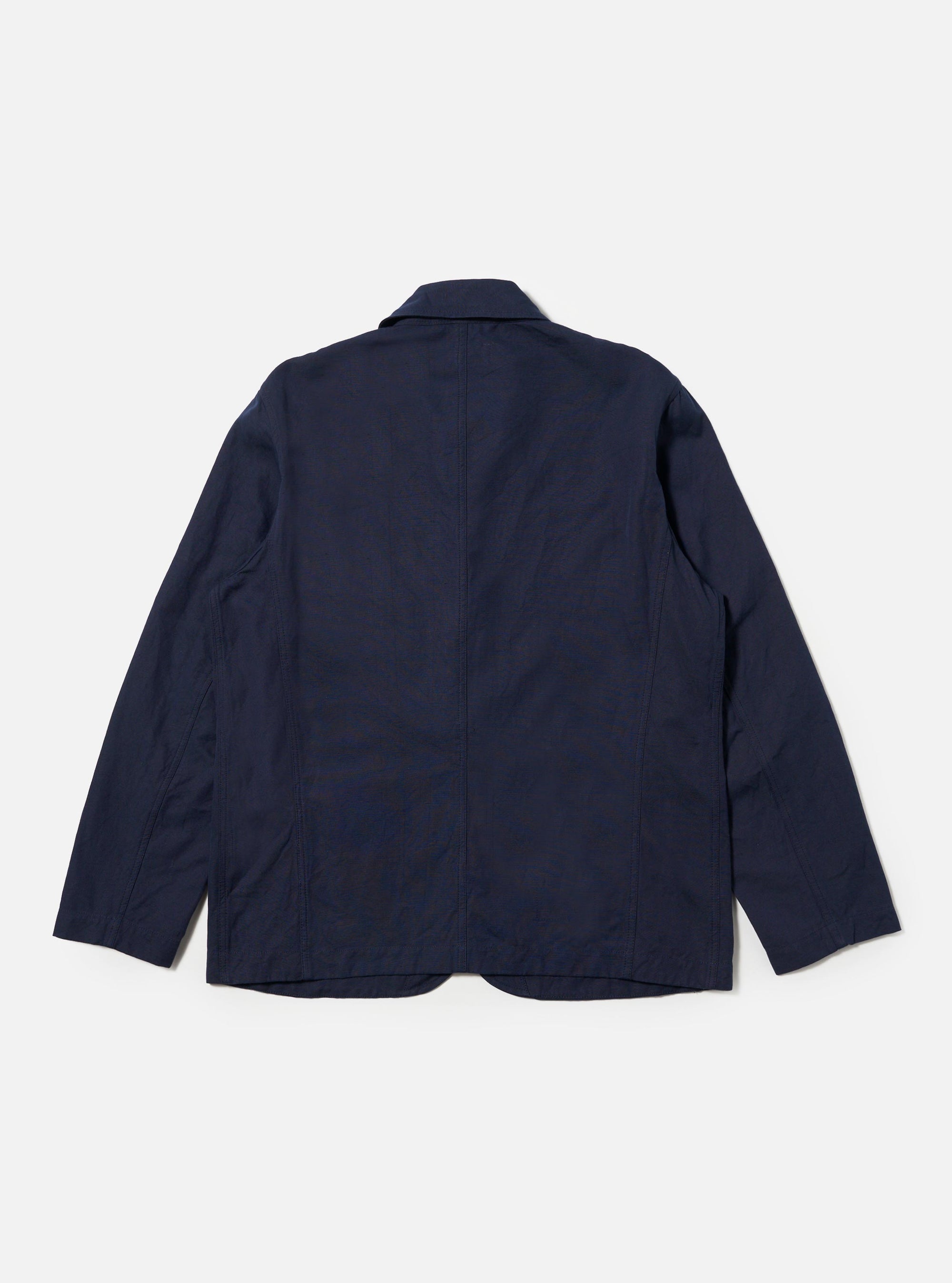 The Navy Linen Slub Weave Bakers Jacket is shown from the back, laid flat against a plain white background. The image highlights the textured navy blue slub weave fabric, a central vertical seam, and the straight hem of the garment.