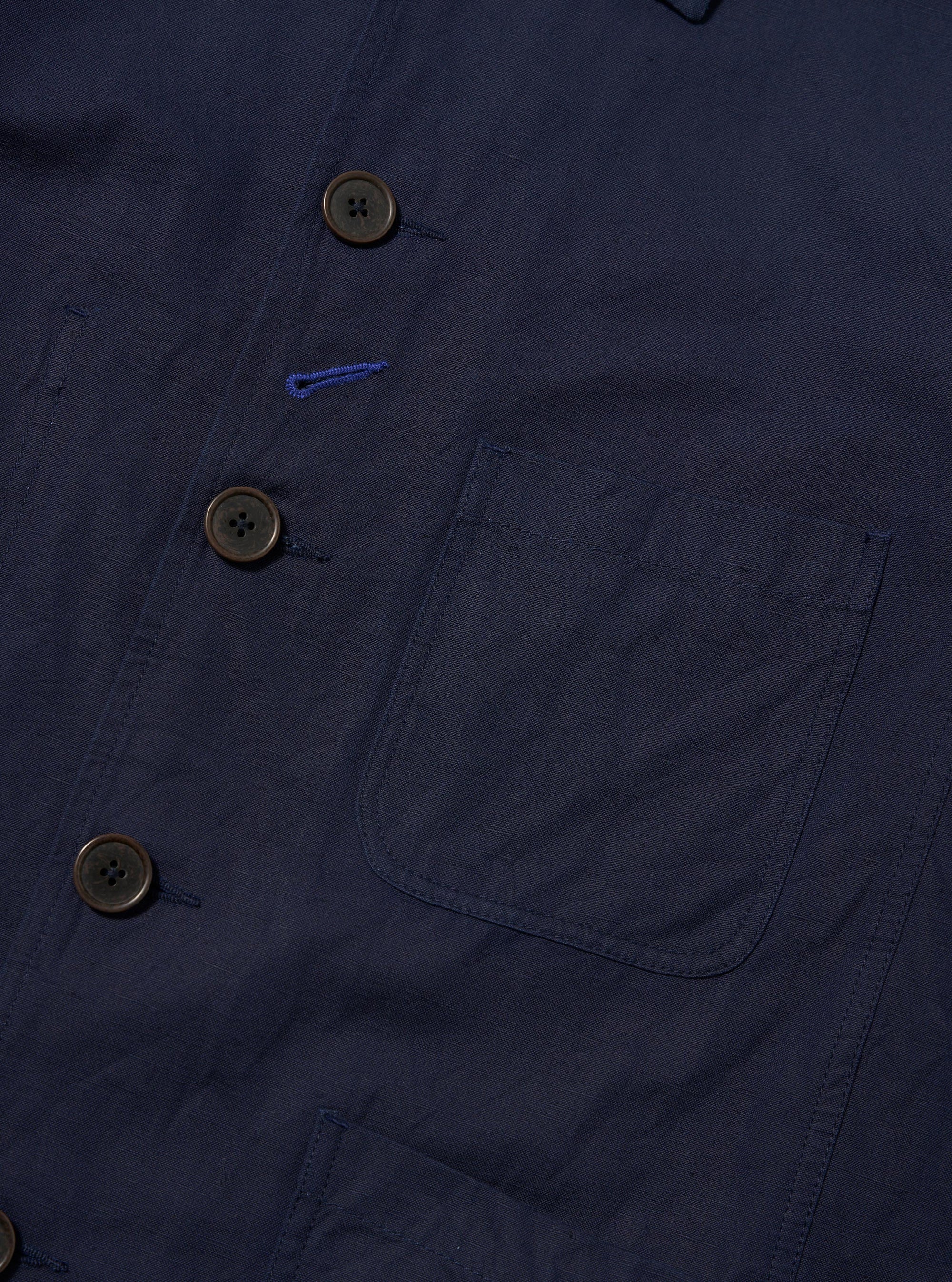 The Navy Linen Slub Weave Bakers Jacket is shown from the back, laid flat against a solid white background. The image highlights the textured navy blue linen-cotton blend fabric, featuring a two-piece sleeve construction and a centered back vent.
