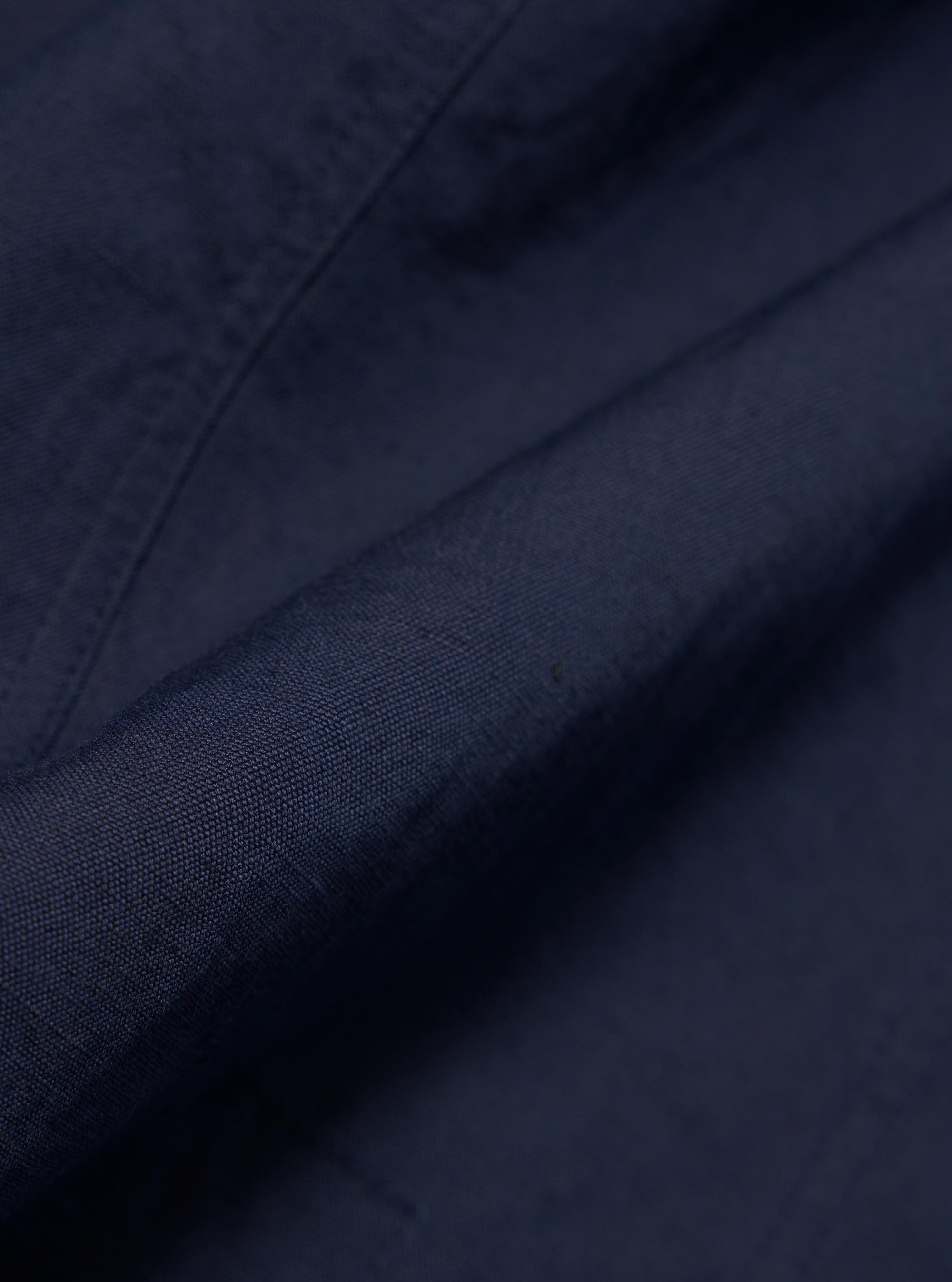 A close-up fabric swatch of the Navy Linen Slub Weave Bakers Jacket shows the deep navy blue color and the distinct, irregular texture of the linen-cotton blend. The material fills the frame to provide a detailed view of the slubbed weave.