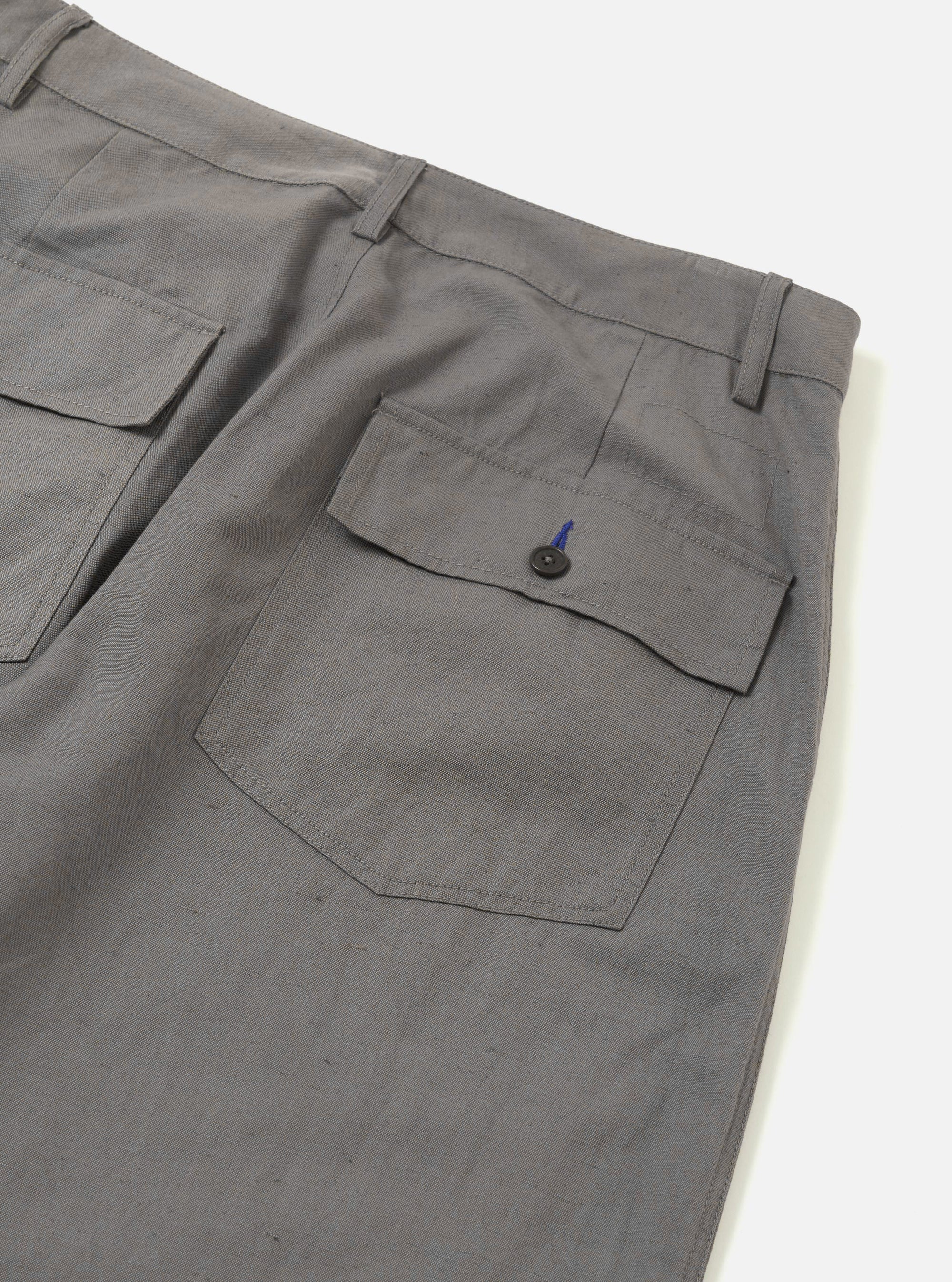 The Mid Grey Linen Slub Weave Dizzy Trouser is shown from the back, laid flat against a plain white background. The image highlights the elasticated waistband and two rear pockets: one with a buttoned flap and one buttoned jetted pocket. The mid-grey fabric features a visible slub weave texture.