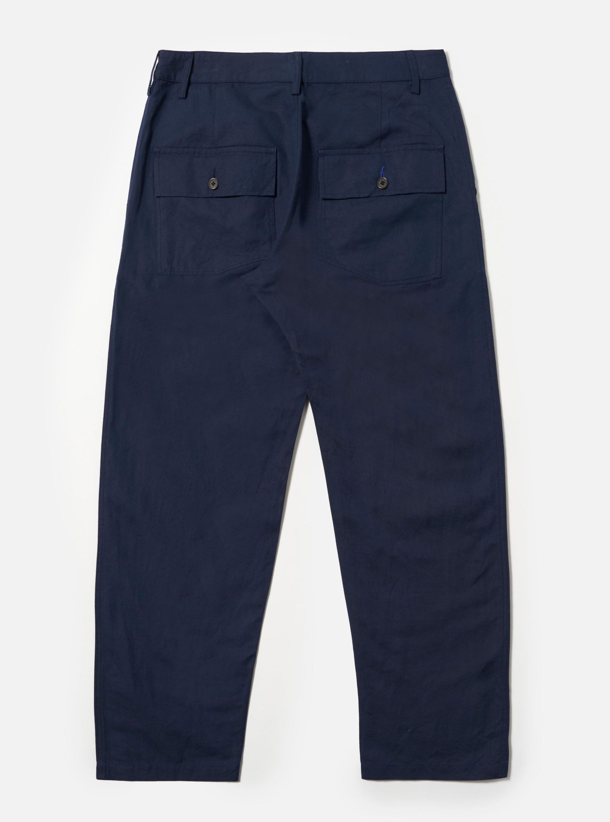The Navy Linen Slub Weave Dizzy Trouser is shown from the back as a flat lay against a plain white background. The image highlights the two large rear buttoned flap patch pockets and the loose, wide-leg cut. The textured navy blue linen-cotton fabric is the primary focus.