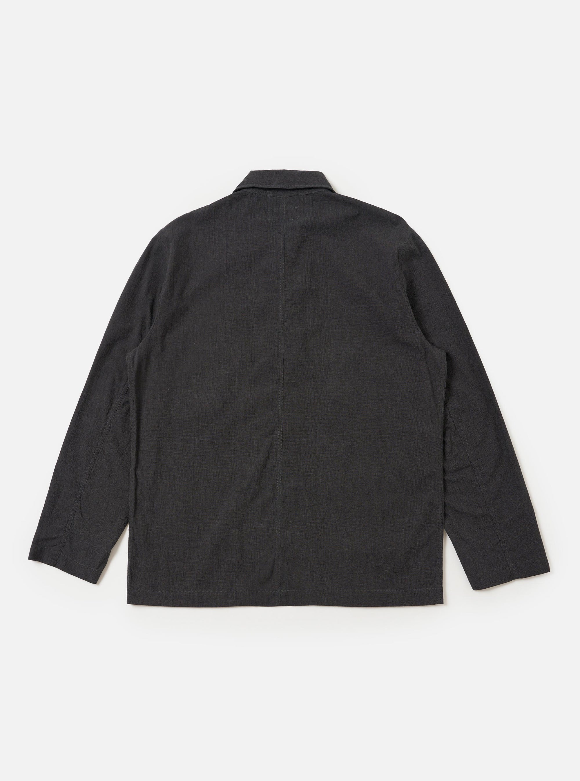 The Charcoal Seattle Cotton OG Bakers Jacket is shown from the back, laid flat against a solid white background. The image highlights the jacket's loose fit, two-piece sleeves, and a central back seam. The charcoal grey fabric features a subtle micro-textured basket weave pattern.