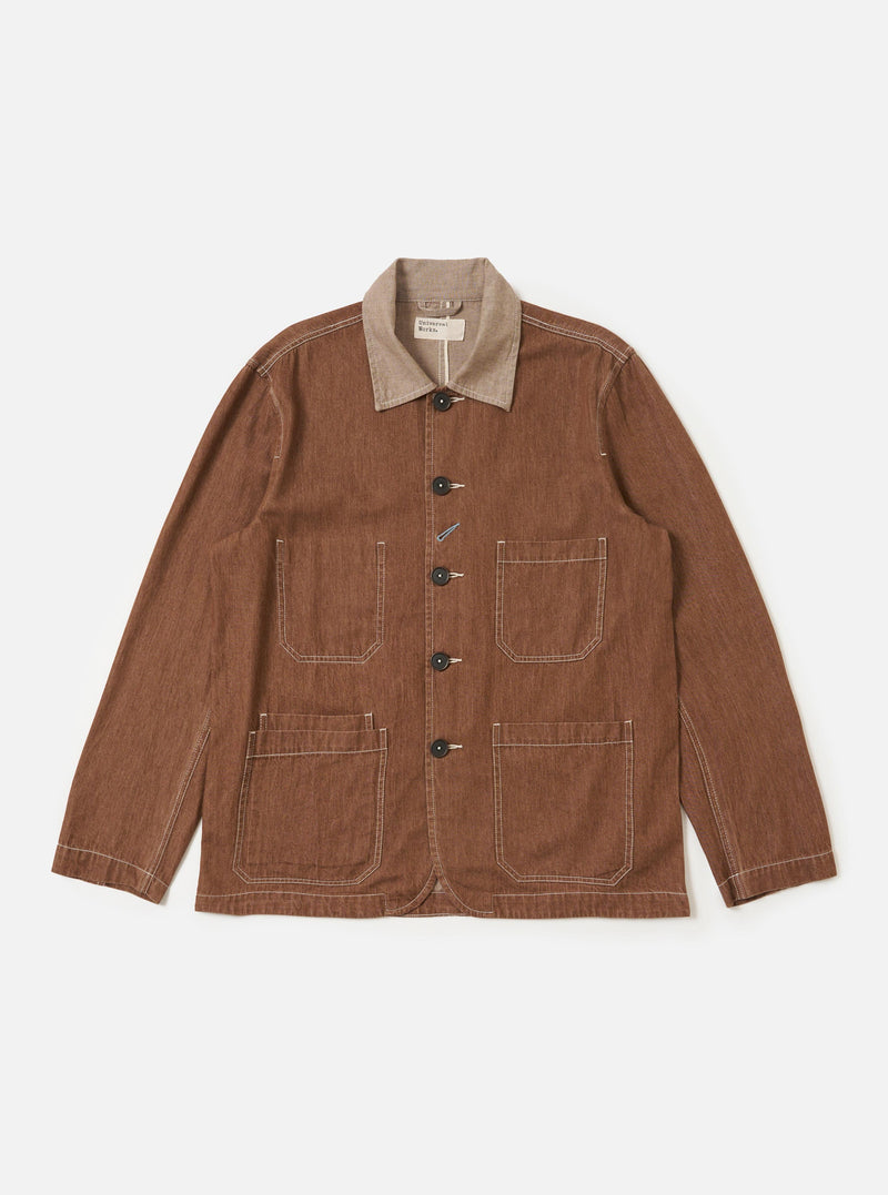 The Brown Meco Denim OG Bakers Jacket is shown laid flat against a solid white background. The jacket features a loose fit, a full button-through front, and a classic pointed collar. Three prominent patch pockets with angled corners are visible on the front, including one chest pocket and two lower pockets, all featuring contrast stitching.